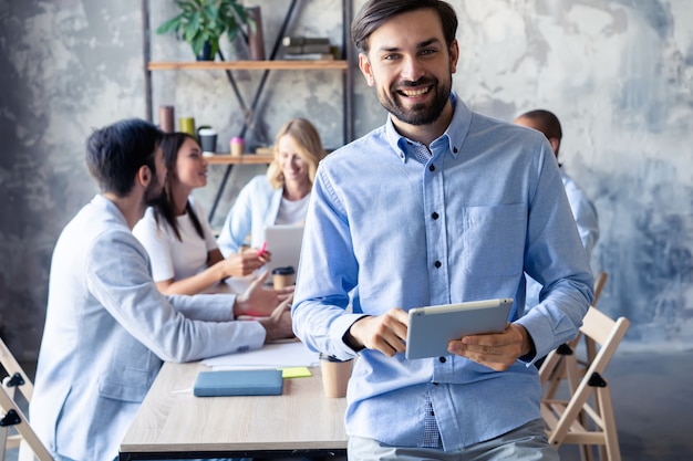 Heureux homme d'affaires intelligent avec des coéquipiers discutant en arrière-plan.