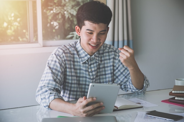 Heureux homme d&#39;affaires prospère gagner, célébrer au bureau et à la recherche de tablette numérique.