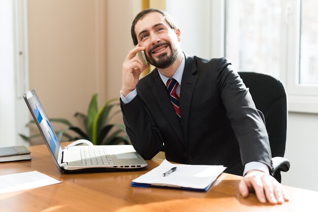 Heureux homme d&#39;affaires prospère souriant parlant sur son téléphone portable