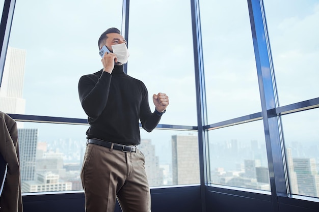 Heureux homme d'affaires avec un smartphone debout près de la fenêtre