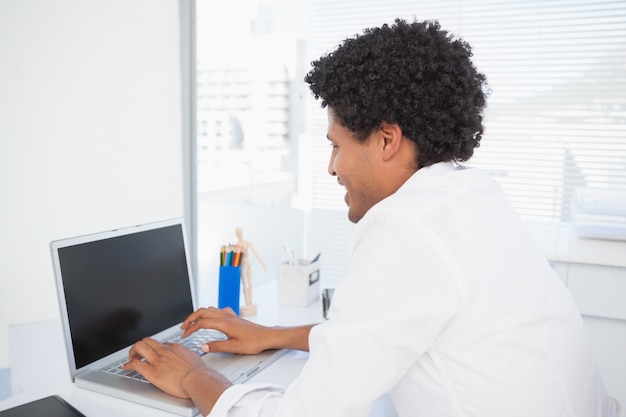 Heureux homme d&#39;affaires en tapant à son bureau