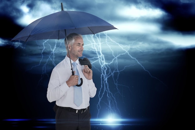 Heureux homme d'affaires tenant un parapluie contre un ciel sombre orageux avec des éclairs