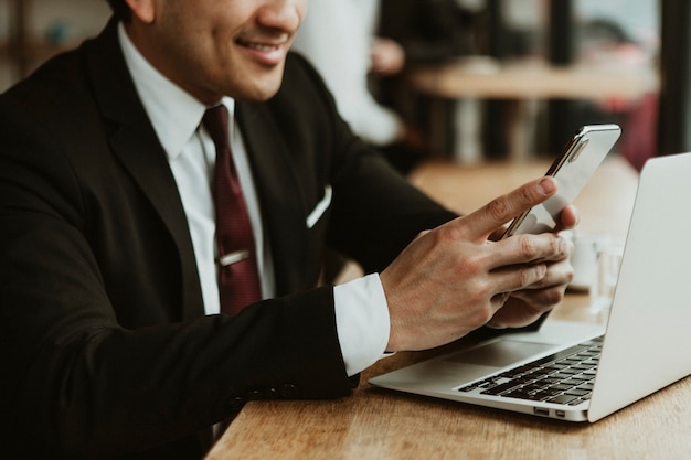 Heureux homme d'affaires utilisant son téléphone dans un café