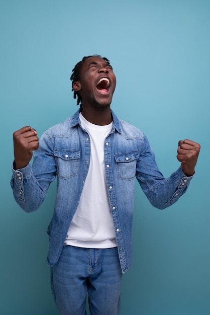 Heureux homme africain joyeux aux cheveux bouclés dans un look décontracté éprouve des émotions agréables