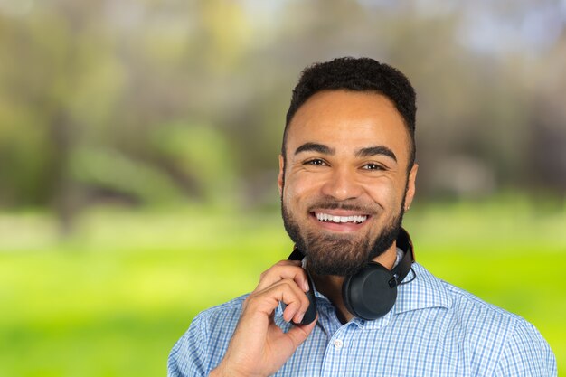 Heureux homme africain souriant en écoutant de la musique dans les écouteurs. fond blanc