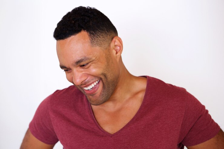 Photo heureux homme afro-américain, regardant vers le bas et souriant sur fond blanc