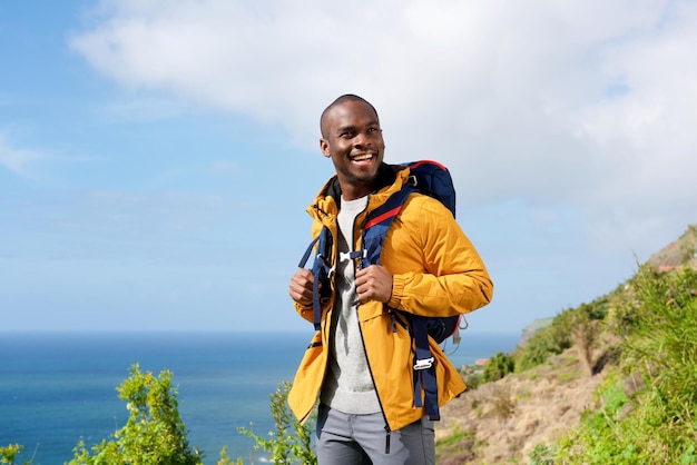 Heureux homme afro-américain avec sac à dos dans la nature