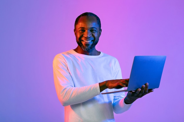 Heureux homme afro-américain tenant un tout nouveau fond néon d'ordinateur