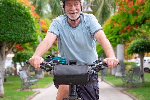 Heureux homme âgé actif faisant du vélo dans le parc public avec un vélo électrique profitant de la liberté Concept de mode de vie sain et de mobilité durable