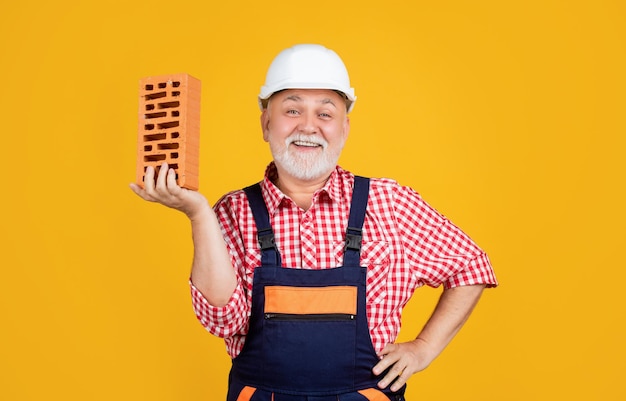 Heureux homme âgé maçon en casque sur fond jaune