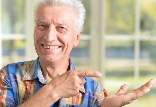 Photo heureux homme âgé à la maison pointant vers la droite