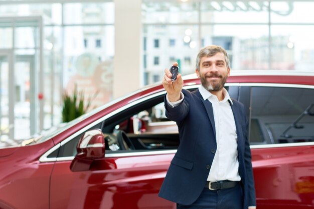 Heureux homme d'âge mûr présentant des clés de voiture