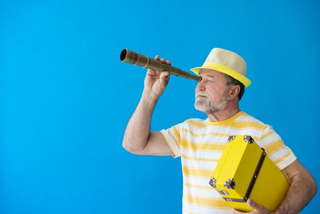 Heureux homme âgé prêt à voyager Personne regardant à travers une longue-vue Vacances d'été et concept de vacances