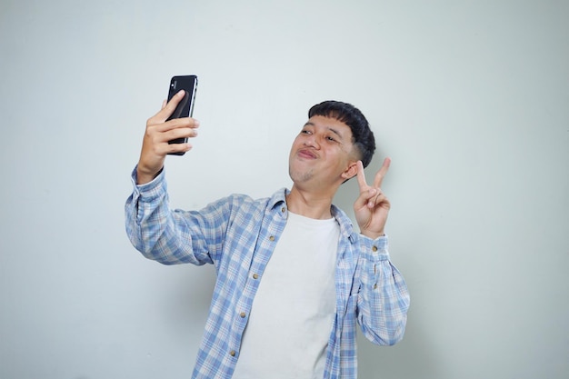 Heureux homme asiatique expression faciale prenant selfie avec appareil photo de téléphone portable