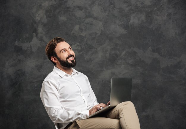 Heureux homme barbu à l'aide d'un ordinateur portable