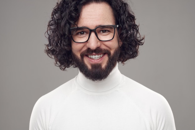 Heureux homme barbu aux cheveux bouclés à lunettes en studio