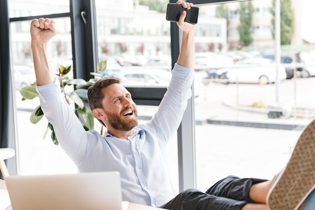 Heureux homme barbu gai au bureau