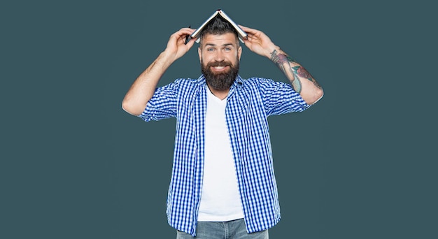 Heureux homme barbu avec un livre sur la tête sur fond gris