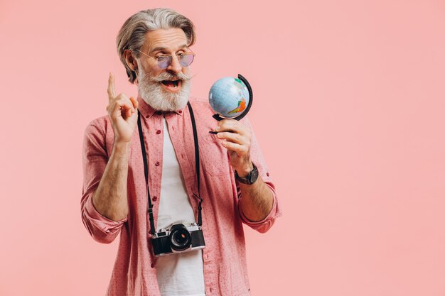 Heureux l'homme barbu à lunettes de soleil avec un appareil photo choisit un pays sur le globe pour voyager.