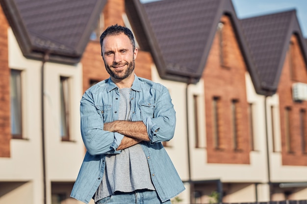 Heureux homme barbu posant près d'une nouvelle maison