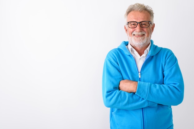 Heureux homme barbu senior souriant avec les bras croisés prêt pour la gym sur blanc