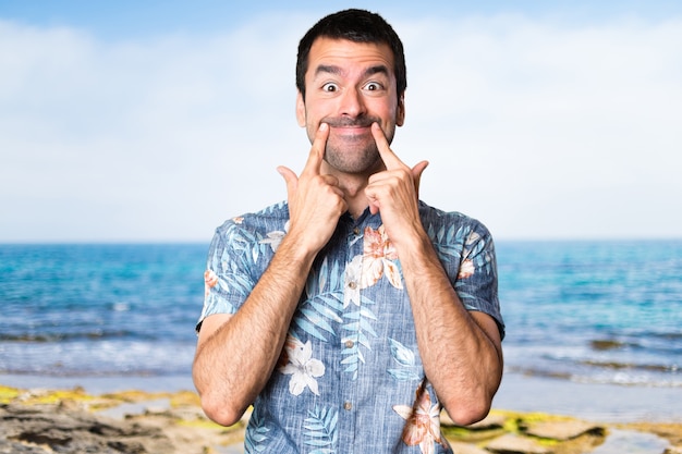 Heureux homme beau avec une chemise à fleurs à la plage