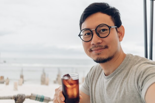 Heureux l'homme boit et se détendre à la plage.