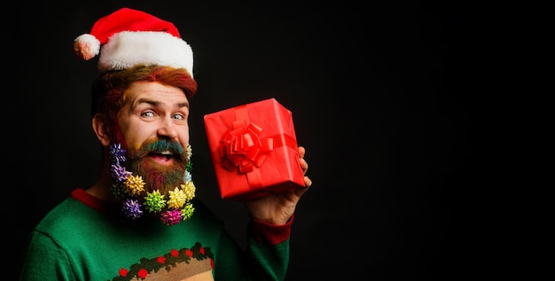 Heureux homme en bonnet de noel et barbe décorée avec cadeau de noël boîte de cadeau de nouvel an