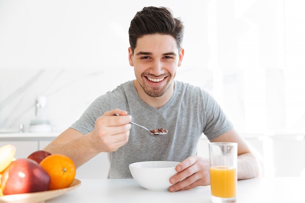 Heureux homme brune assise près de la table et manger