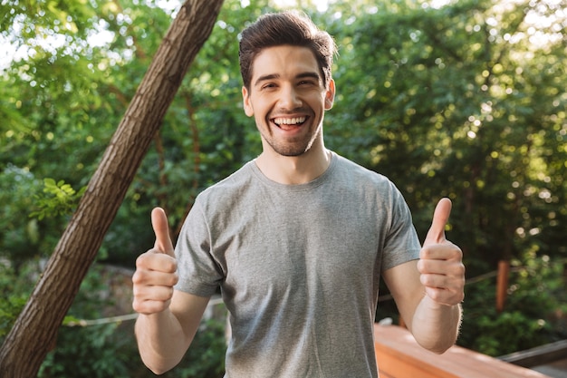 Heureux homme brune en vêtements décontractés montrant les pouces vers le haut