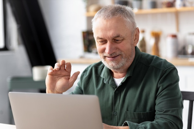 Photo heureux homme caucasien senior utilisant un ordinateur portable pour un appel vidéo assis à la maison