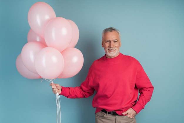 Heureux homme célébrant la tenue de ballons roses.