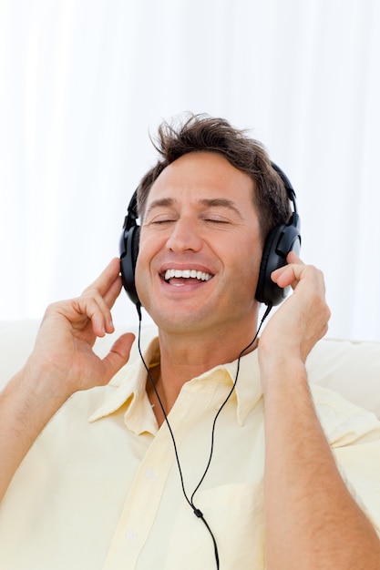 Heureux homme chantant en écoutant de la musique sur le canapé