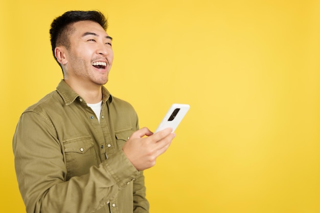 Heureux homme chinois riant tout en utilisant le mobile