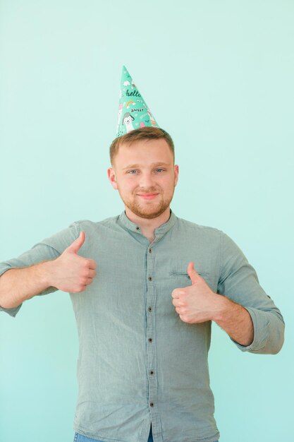 Heureux homme drôle célèbre son anniversaire en compagnie d'amis porte une casquette de vacances sur la tête