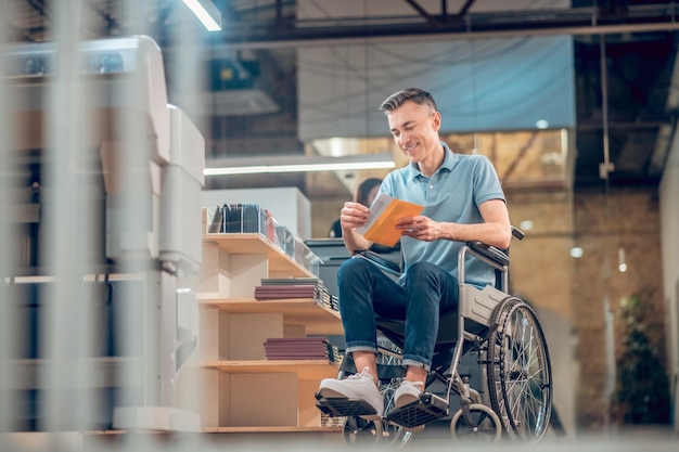 Heureux homme en fauteuil roulant en regardant l'enveloppe avec carte postale