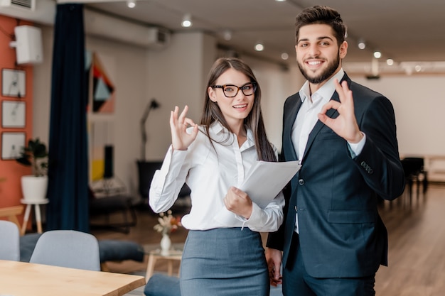 Heureux homme et femme dans le bureau montrent ok geste