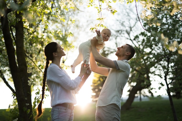 Heureux homme et femme jouant avec bébé à l'extérieur