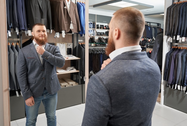 Heureux homme fort essayant un costume classique dans un magasin de vêtements