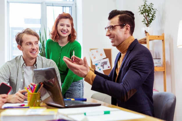 Heureux homme gai souriant tout en parlant d'affaires à ses étudiants