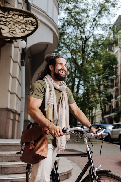 Heureux homme heureux souriant tout en utilisant son vélo dans la ville