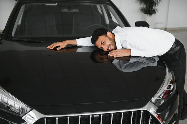 Heureux homme indien vérifiant les caractéristiques de la voiture dans la salle d'exposition