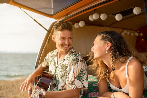 Heureux homme jouant de la guitare à côté d'une femme dans une camionnette