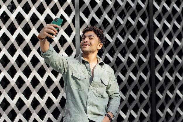 Heureux homme latin prenant un selfie sur fond à motifs