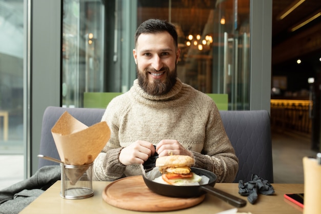 Heureux homme mangeant un hamburger au restaurant