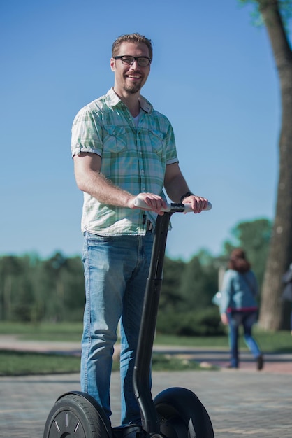 Photo heureux homme moderne chevauchant un mini hoverboard dans le parc le concept de loisirs