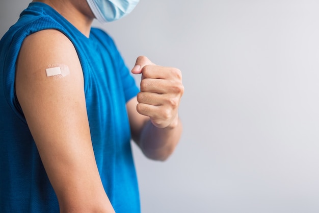 Heureux homme montrant son bras avec un bandage après avoir reçu le vaccin. Vaccination, immunisation, inoculation et pandémie de coronavirus (Covid-19)