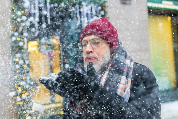 Heureux homme mûr dans le marché de Noël d'hiver à l'extérieur avec paysage urbain en arrière-plan