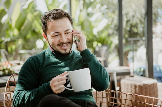 Heureux homme parlant au téléphone dans un café
