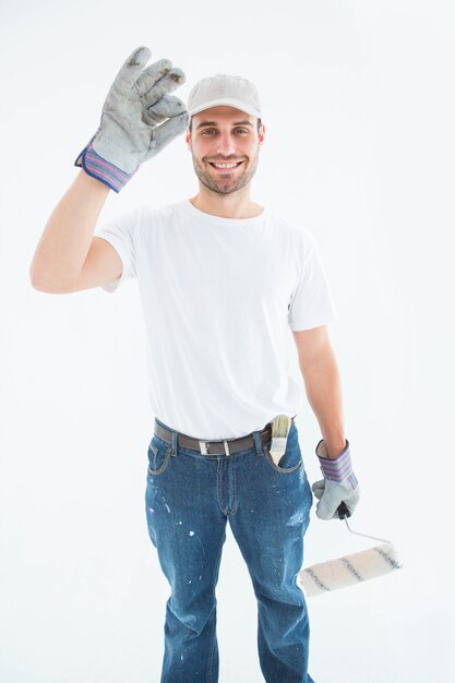 Heureux homme portant des gants tout en tenant le rouleau à peinture